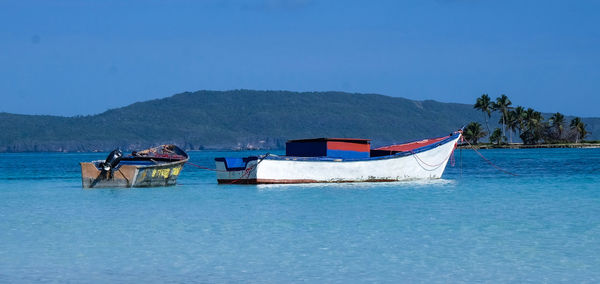 Boat moored on sea against clear blue sky