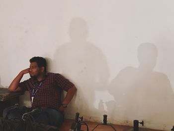 Rear view of men looking at man sitting against wall