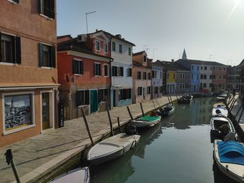 Boats moored in canal amidst buildings in city