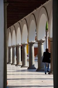 Rear view of person leaning on column in corridor