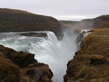 Scenic view of waterfall against cloudy sky