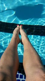 Low section of man relaxing in swimming pool