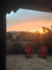 Chairs and trees against sky during sunset