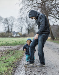 Full length of father with daughter standing on road during winter