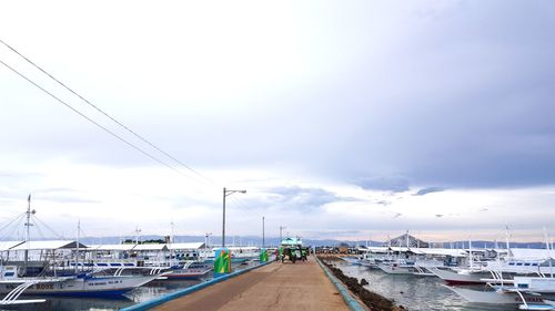 Boats moored at harbor against sky