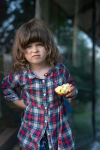 Girl holding apple while standing in backyard