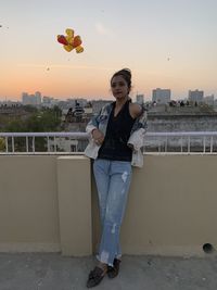 Portrait of young woman standing against orange sky