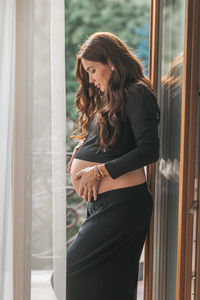 Young woman looking through window