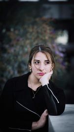 Close-up of young woman looking away while sitting outdoors