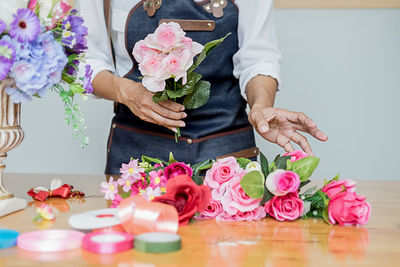 Low section of woman with pink roses on table