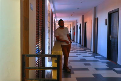 Full length of young woman standing in corridor of building