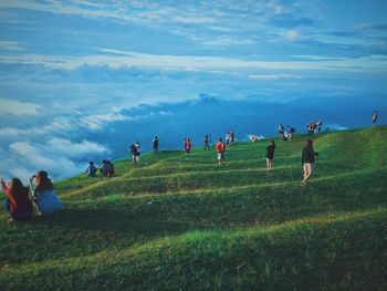 People enjoying at grassy landscape against sky