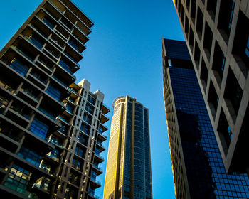 Low angle view of modern buildings against clear blue sky