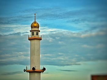 Low angle view of lighthouse by building against sky