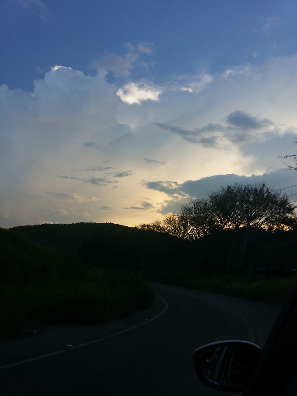 sunset, car, transportation, road, dusk, cloud - sky, mode of transport, tree, land vehicle, the way forward, driving, sky, no people, outdoors, beauty in nature, illuminated, nature, night, mountain, winding road