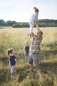 Father with daughters and son on land against during picnic