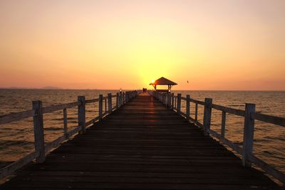 Pier over sea against sky during sunset