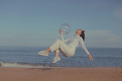 Rear view of woman standing at beach against clear sky