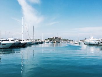 Sailboats moored in river against sky