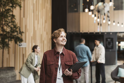 Smiling male entrepreneur looking away while standing at convention center