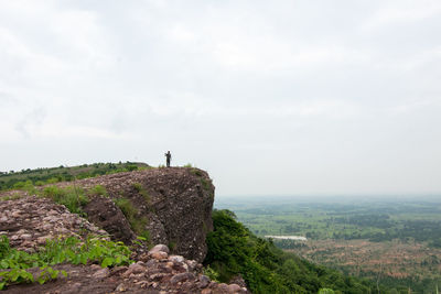 Man standing on rock against sky