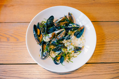 Close up of freshly cooked mussles in a plate with ingredients.