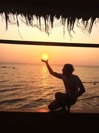 Silhouette woman on beach against sky during sunset