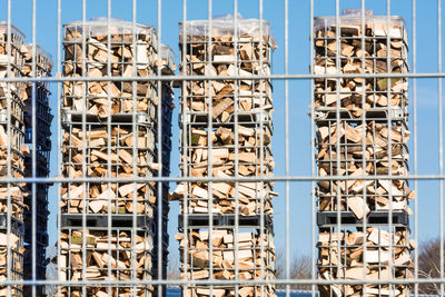 Logs in metal container seen through fence