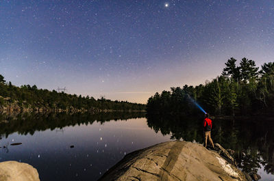 Man standing by lake against sky at night