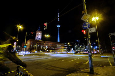 Illuminated light trails on city street by buildings at night