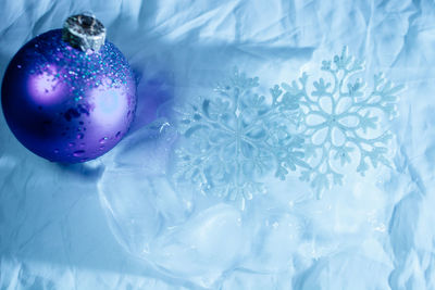 Close-up of blue christmas decoration by snowflakes and ice