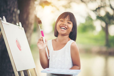 Portrait of happy girl painting on canvas