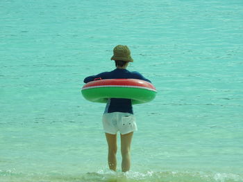 Rear view of woman with inflatable ring standing in sea
