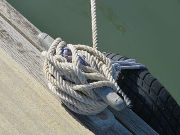 High angle view of rope tied on bollard at pier by river during sunny day