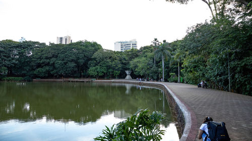 Reflection of trees in river against sky in city