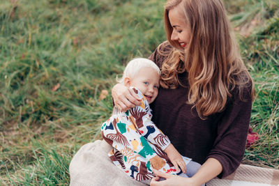 Mother with cute daughter sitting on grassy land