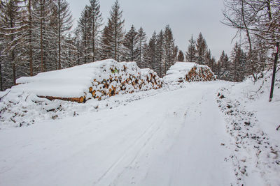 Snow covered field by trees against clear sky