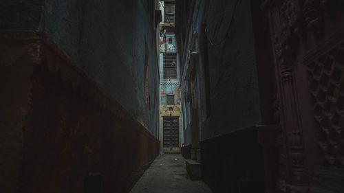 Narrow alley amidst buildings in city at night