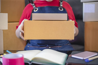 Midsection of person holding book while sitting in box