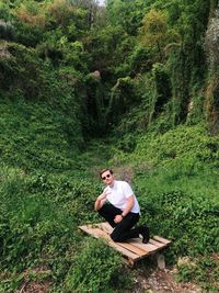 Full length of man climbing on tree in forest