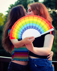 Rear view of woman holding multi colored umbrella