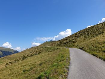 Road leading towards mountains against blue sky