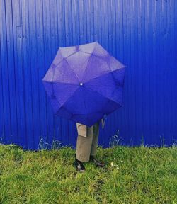 Low section of man holding umbrella standing on grass