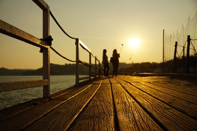 Silhouette people on pier against sky during sunset