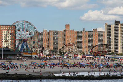 Crowd at beach against sky in city