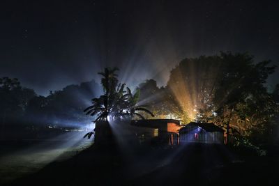 Dramatic light ray coming from the back of a house of rural area at night time under starry sky
