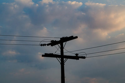 Low angle view of silhouette electricity pylon against sky