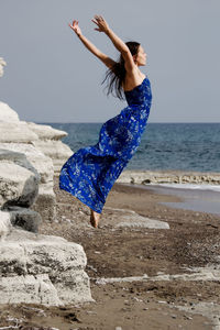 Young woman jumping in sea against clear sky