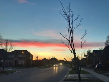 Cars on road against sky at sunset