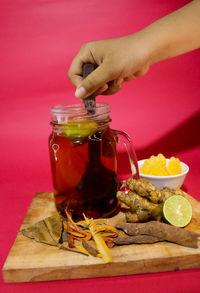 Midsection of man holding drink in glass jar on table